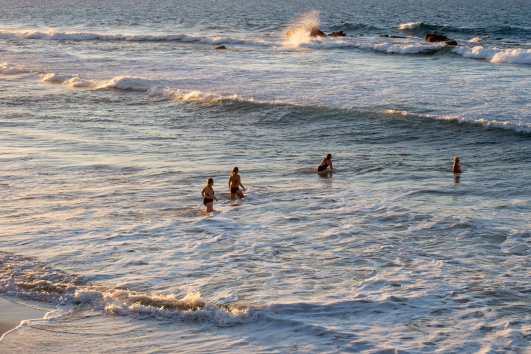 Menschen im Meer bei warmem Abendlicht